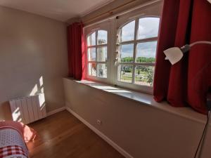 Habitación con una ventana con cortinas rojas y una lámpara. en Phare des Impressionnistes, en Honfleur