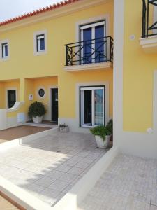ロウリニャンにあるGrillohouseのパティオとバルコニー付きの広い黄色の家です。