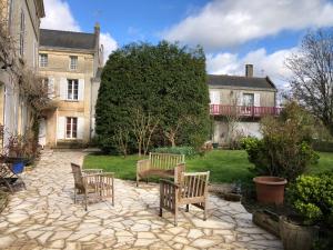 two benches sitting on a patio in front of a house at Le Chai De La Rose SPA et Séances Bien être in Doué-la-Fontaine