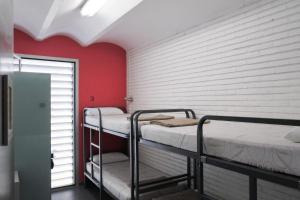 バルセロナにあるHelloBCN Youth Hostel Barcelonaの赤い壁の客室で、二段ベッド2組が備わります。