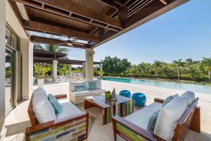 een terras met een tafel en stoelen en een zwembad bij Unique Private Villa with Pools and Golf Cart in La Romana