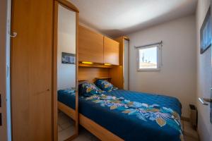 Schlafzimmer mit einem Bett mit blauer Bettwäsche und einem Fenster in der Unterkunft T2 en hypercentre -parking privé-clim-proche plage in Sainte-Maxime