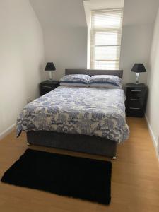 a bedroom with a bed and two night stands and a window at Eastgate Apartment in Inverness