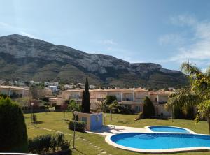 uma villa com piscina e montanhas ao fundo em El Respiro verde em Denia