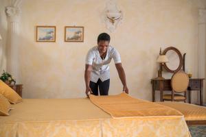 a woman is making a bed in a room at Hotel Il Girasole in Anacapri