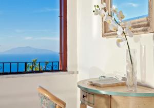 a table with a vase of flowers and a window at Hotel Il Girasole in Anacapri
