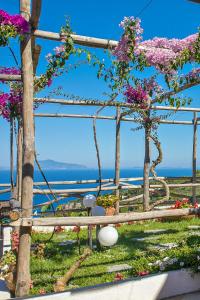 a fence with flowers on it with the ocean in the background at Hotel Il Girasole in Anacapri