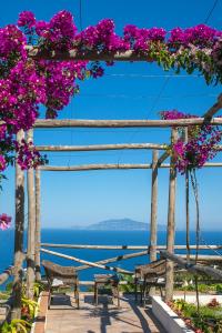 a pergola with two benches and purple flowers at Hotel Il Girasole in Anacapri