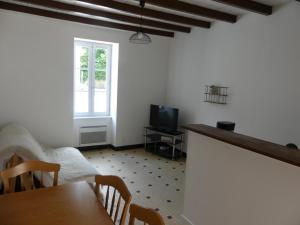uma sala de estar com uma mesa e uma televisão em Petit gite du Puy Lambert em La Flocellière