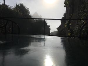 een door regen doordrenkte straat met de zon op de achtergrond bij L’Auberge du Sombral in Saint-Cirq-Lapopie