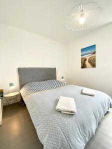 um quarto branco com uma cama grande e toalhas em T2 Hyper cosy Plage et port à pieds em Ploemeur