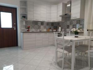 a kitchen with white cabinets and a table and chairs at AMAA CASA in Vico Equense