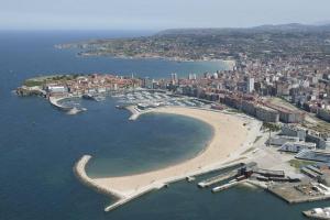 an aerial view of a beach with boats in the water at APARTAMENTO 1ºLINEA PLAYA PONIENTE in Gijón