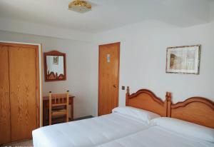 a bedroom with two white beds and a wooden headboard at Hostal Pirineos Meliz in Bielsa