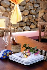 a wooden table with a plate of food and wine glasses at Dammusi di Sofia in Pantelleria