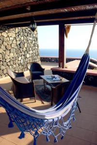 a blue hammock on a patio with a table and chairs at Dammusi di Sofia in Pantelleria