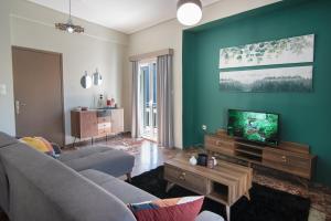 uma sala de estar com um sofá e uma televisão de ecrã plano em Emerald 110m2 entire floor apt steps to city’s heart em Kalamata
