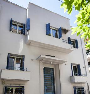 biały budynek z niebieskimi okiennicami w obiekcie Bentzi...Boutique Apartment in Pangrati, Superior Suite (2) for 4 guests w Atenach