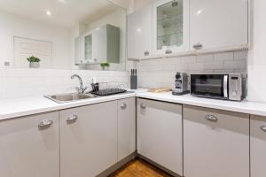 uma cozinha branca com um micro-ondas e um lavatório em Stylish Apartment in the heart of Newcastle centre em Newcastle upon Tyne