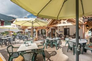 an outdoor patio with tables and chairs and umbrellas at Hotel Ghezzi in Andalo