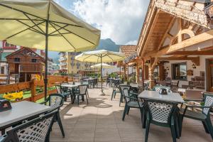 an outdoor patio with tables and chairs and umbrellas at Hotel Ghezzi in Andalo