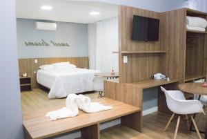 a bedroom with a bed and a table and a tv at Hotel Alvorada - Trindade do Sul in Trindade