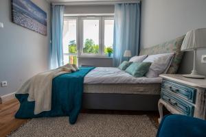 - une chambre avec un lit doté de rideaux bleus et d'une fenêtre dans l'établissement Apartamenty Na Żmijowej Górce, à Debina