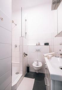 La salle de bains blanche est pourvue de toilettes et d'un lavabo. dans l'établissement Sleep Point, à Brême