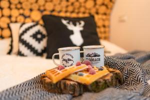 ザコパネにあるWilla Bianco Zakopaneのベッドの上に食料トレイとコーヒーカップ2杯