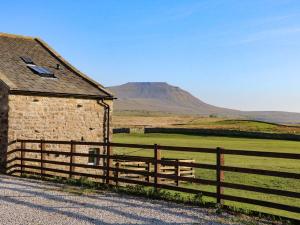 a barn with a fence and a mountain in the background at Three Peaks Barn in Carnforth