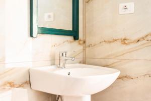 a white sink in a bathroom with marble walls at Janakis Garden Livadi Beach in (( Spile ))