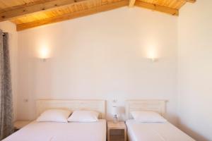 two beds in a room with white walls and wooden ceilings at Janakis Garden Livadi Beach in (( Spile ))