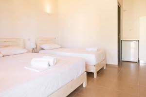 two beds in a room with white walls at Janakis Garden Livadi Beach in (( Spile ))