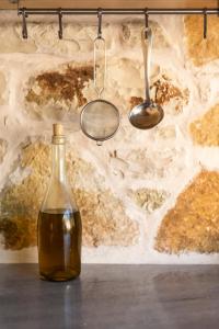 a bottle of oil sitting on a table in front of a stone wall at Janakis Garden Livadi Beach in (( Spile ))