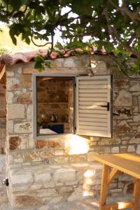 a stone building with a window with a shutter at Janakis Garden Livadi Beach in (( Spile ))