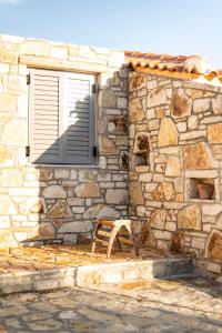 a window with a bench in front of a stone building at Janakis Garden Livadi Beach in (( Spile ))