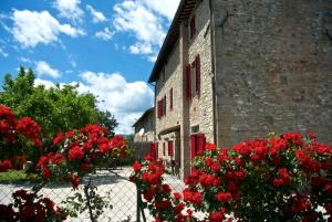 un edificio in mattoni con fiori rossi accanto a una recinzione di Casa Donella B&B a Gricignano