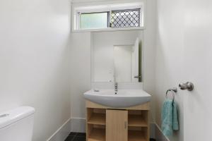 ein weißes Badezimmer mit Waschbecken und Fenster in der Unterkunft Amalfi in Point Lookout + 7 Fotos