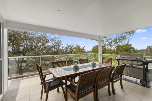 ein Esszimmer mit einem Tisch, Stühlen und einem Grill in der Unterkunft Amalfi in Point Lookout