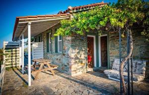 a small stone house with a picnic table on a patio at Toumba Eco Farm Guesthouses in Plomarion