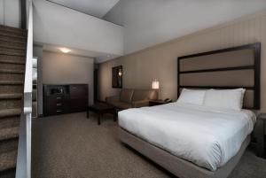 a hotel room with a bed, chair, and nightstand at Prestige Vernon Hotel in Vernon