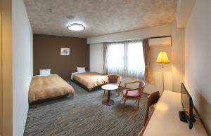 una camera d'albergo con due letti e un tavolo di Hotel Crown Hills Toyohashi a Toyohashi