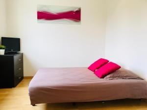 uma cama com uma almofada rosa num quarto em La Gaude, villa 6 personnes-jardin-piscine-vue dégagée au calme em La Gaude
