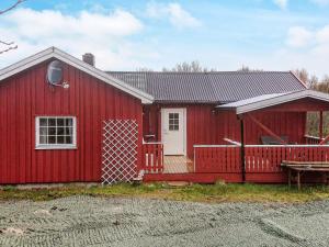 a red barn with a white door and a porch at 6 person holiday home in Storfosna-By Traum in Sletta