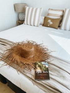 a bed with a book and a straw hat on it at Pineapple Studio Byron Bay in Byron Bay