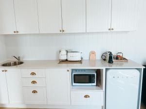 a kitchen with white cabinets and a white microwave at Pineapple Studio Byron Bay in Byron Bay