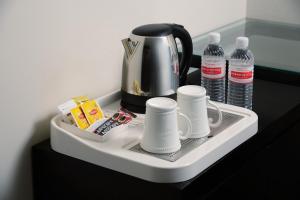 een dienblad met een koffiepot, kopjes en water bij E-RED HOTEL KUANTAN in Kuantan