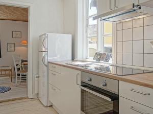 グドイェムにある2 person holiday home in Gudhjemの白いキッチン(冷蔵庫付)、窓