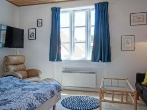 グドイェムにある2 person holiday home in Gudhjemのベッドルーム1室(ベッド1台、青いカーテン付きの窓付)