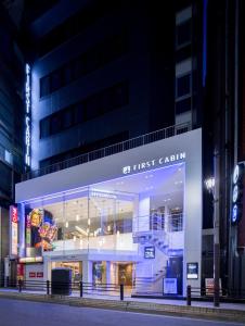 a city street at night with a neon sign at First Cabin Akasaka in Tokyo